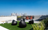 Breathtaking rooftop lounge with modern seating, lush greenery, and stunning city skyline views under a clear blue sky.
