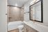 Elegant bathroom interior featuring a modern vanity with a gold-framed mirror, polished fixtures, and a cozy shower area with soft lighting.