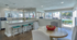 Bright and inviting dining area in a modern apartment with large windows overlooking a pool, featuring stylish seating and a spacious countertop.