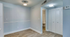 Inviting apartment entryway with sleek wood floors, soft blue walls, and ample closet space, leading to a modern bathroom.