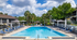 Inviting outdoor pool area with plenty of sun loungers, shaded umbrellas, and lush greenery in a tranquil residential complex.