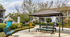 Charming outdoor space with a modern gazebo, picnic benches, vibrant greenery, and a serene ambiance in a residential community.