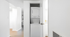 Modern apartment hall with sleek integrated laundry unit and elegant white interiors.