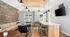 Chic communal space featuring a rustic stone wall, modern lighting, and a sleek kitchen bar area, perfect for social gatherings.