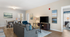 Elegant living room featuring modern furniture, cozy armchairs, and a sleek flat-screen TV, leading into a tastefully decorated bedroom with ample natural light.