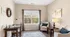 Bright and inviting home office with elegant furnishings, featuring a spacious desk, comfortable seating, and scenic forest views through a large window.