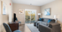 Charming living room with elegant gray sofa, bright accents, and a balcony view. Perfect for relaxing and entertaining.