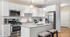 Modern kitchen with sleek stainless steel appliances, elegant white cabinetry, and a stylish breakfast bar with chic lighting.