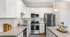 Modern kitchen with sleek granite countertops, stainless steel appliances, elegant pendant lighting, and ample white cabinetry.