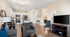 Open-concept living room with modern kitchen, featuring sleek white cabinets, stainless steel appliances, and cozy seating area.