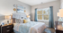 Bright and inviting bedroom with elegant decor, featuring a plush headboard, modern bedside lamps, and serene wall art next to a large window with scenic views.