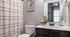 Modern bathroom with stylish patterned shower curtain and eye chart wall art.