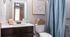 Modern bathroom with stylish patterned shower curtain and eye chart wall art.