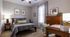 Cozy bedroom with a neatly made bed, stylish decor, and natural light streaming through a window.