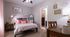 Cozy bedroom with a neatly made bed, stylish decor, and natural light streaming through a window.