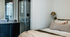 Elegant bedroom with modern decor, featuring a large window, stylish furnishings, and a calming color palette.