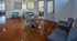 Chic and modern apartment lounge featuring stylish blue seating, a cozy round table with a potted plant, and a view of a sophisticated dining area through the doorway.