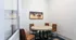 Cozy meeting room with round table, four plush chairs, and a vibrant horse racing painting on the wall.