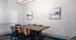 Elegant meeting room featuring a sleek rectangular table with six chairs, modern chandelier, and abstract wall art for a professional setting.