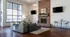 Chic living area with large window, stylish exposed brick fireplace, modern furniture, and elegant decor.