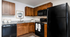 Modern kitchen with elegant wooden cabinets, sleek black appliances, and a stylish granite countertop.