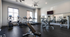 Modern fitness center with state-of-the-art equipment including treadmills, elliptical machines, and weight benches in a bright and spacious room.