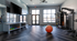 Modern fitness room with large windows, equipped with a variety of weights, a punching bag, and an exercise ball, offering a bright and inviting workout space.