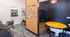 Chic and inviting workspace with vibrant yellow tables, comfortable seating, and a cork board displaying cheerful photos under 'Good Times'.
