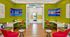 Inviting and vibrant lobby space with modern decor, showcasing bright green walls and comfortable seating accented by striking wall art and sleek wooden floors.
