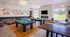 Elegant recreation room boasting two pool tables, modern seating, and large windows for natural light, perfect for relaxation and entertainment.