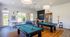 Inviting game room with two billiard tables, sleek lighting, and modern furnishings creating a vibrant social space.