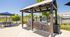 Charming outdoor grilling area with twin barbecue stations, cozy seating under blue umbrellas, and lush greenery. Perfect for entertaining and enjoying sunny days.