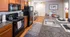Modern kitchen with granite countertops, wooden cabinets, and sleek black appliances, leading into a cozy dining area. Elegant design with a warm ambiance, perfect for culinary enthusiasts.