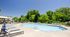 Inviting outdoor swimming pool surrounded by sleek lounge chairs and lush greenery, perfect for relaxation and enjoyment on sunny days.