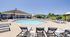 Inviting outdoor pool area with elegant lounge chairs, umbrellas, and a charming poolside pavilion under a clear blue sky.
