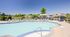 Inviting outdoor pool area with stylish lounge chairs and umbrellas, perfect for relaxation under clear blue skies.