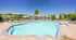 Inviting outdoor pool area with pristine waters, surrounded by elegant lounge chairs and beautiful landscaping in a vibrant community setting.