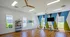 Bright, modern fitness room with hardwood floors, vibrant geometric accent wall, stationary bikes, and large windows overlooking greenery.
