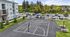 Inviting outdoor sports complex featuring a modern basketball court, adjacent to a stylish apartment building, ample parking, and scenic landscaped greenery.