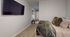 Cozy bedroom with stylish decor, featuring a wall-mounted TV, soft plush bedding, and a wooden bench, creating a modern yet inviting atmosphere.