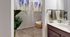 Inviting walk-in closet with plush carpet and ample shelving, complemented by a modern bathroom vanity and lush greenery, offering a perfect blend of style and functionality.