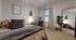 Inviting bedroom with plush bedding, elegant decor, and a cozy workspace by the window, enhanced with natural light and a stylish floor-length mirror.