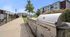 Modern outdoor barbeque area in a vibrant apartment complex, featuring sleek stainless steel grills and lush greenery.