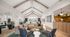 Contemporary living area featuring vaulted ceilings, stylish leather sofa, modern armchairs, and vibrant decor with natural light streaming in.
