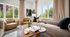 Bright and inviting living room with cozy beige sofas, a stylish wooden coffee table, and expansive windows showcasing lush greenery.
