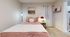 Cozy bedroom with elegant decor featuring a plush pink bed, warm lighting, and artistic accents creating a serene retreat.