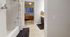 Inviting apartment bathroom with modern fixtures leading into a cozy bedroom with large window views.