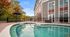 Inviting apartment complex with a sparkling outdoor pool, surrounded by lush greenery and vibrant trees, perfect for relaxation and leisure.