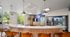 Modern communal area with sleek marble countertop, stylish leather chairs, and vibrant vending machines near large windows overlooking greenery.