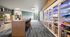Inviting modern lobby with sleek wooden table, stylish seating, and sunny window. Shelving with a variety of products enhances the vibrant feel.